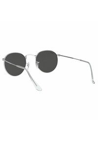 Occhiali da sole rotondi con lenti scure, montatura in metallo argentato, aste sottili e supporti per il naso regolabili. Design chiaro e minimalista con una finitura elegante.