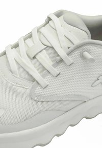 Scarpa sportiva bianca con tomaia in rete, lacci piatti, linguetta imbottita e suola in gomma testurizzata con un motivo a onda lungo il bordo.