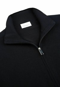 Czarna bluza rozpinana z wysokim kołnierzem, prążkowymi mankietami i srebrnym zamkiem błyskawicznym. Metka z napisem "PROFUOMO" zawiera informacje o rozmiarze.