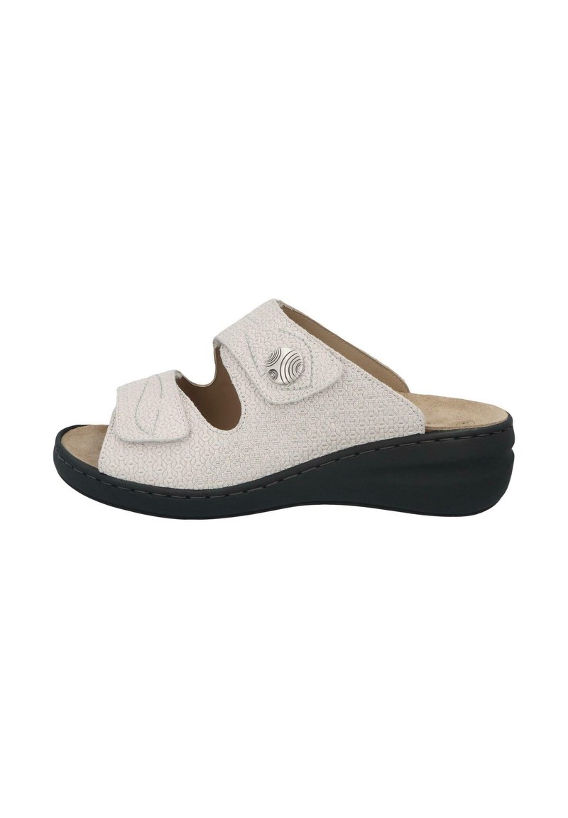 White slip-on sandals with a textured upper, featuring two adjustable straps, circular accents, and a black wedge sole.