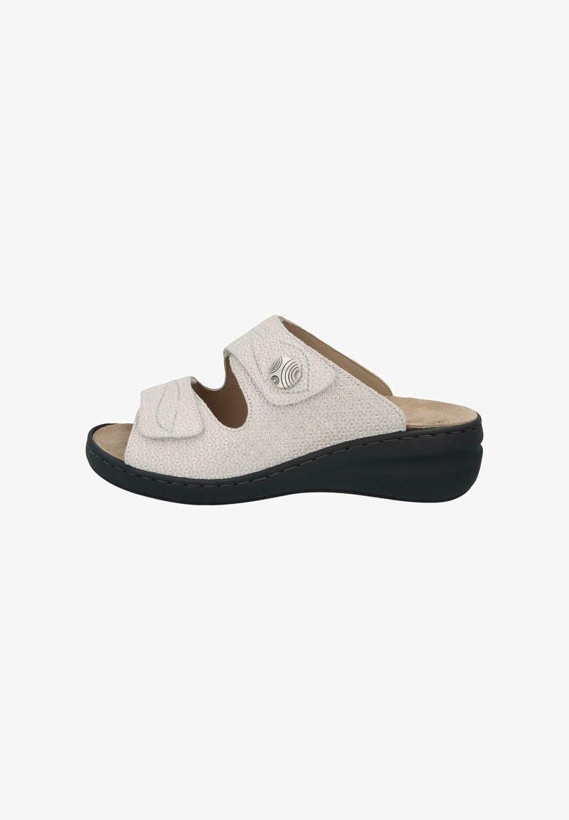 White slip-on sandals with a textured upper, featuring two adjustable straps, circular accents, and a black wedge sole.