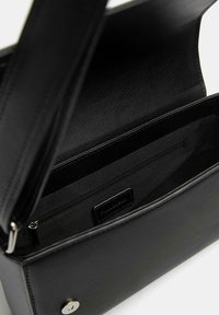 Borsa a mano nera in pelle con una texture liscia, dotata di chiusura a scatto magnetico e una tasca interna con zip per un'ottimale organizzazione.