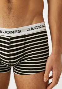Fekete-fehér csíkos boxeralsó fehér derékszíjjal, melyen világosszürkével a "JACK & JONES" felirat található. Puha anyag és testhezálló fazon.