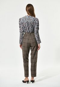 Die blumenmusterte Bluse hat Puffärmel, während die karierten, hoch taillierten Hosen einen schmalen Schnitt und eine verkürzte Länge haben.