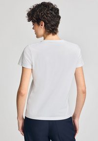 Witte katoenen T-shirt met korte mouwen, ronde hals en een getailleerde pasvorm. Glad textuur zonder patronen of versieringen.