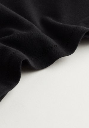 Zwarte stof met een gladde textuur, die een geraffineerde rand en subtiele stikseldetails toont, rustend op een lichtgekleurde ondergrond.