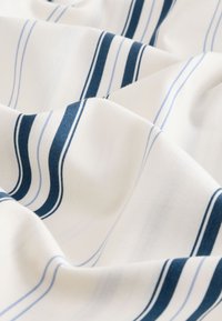 Tissu blanc avec des rayures horizontales bleu marine et bleu clair. La texture semble douce et lisse, avec de légers plis et froissements.