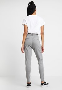 Šedé slim-fit tepláky s elastickým pasem a bočními kapsami, kombinované s bílým tričkem s krátkým rukávem a černými teniskami.