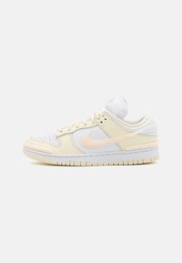 Nike Sneaker mit beigem Leder- und Mesh-Obermaterial, pastellrosa Akzenten, perforierter Zehenbox und weißer Gummisohle mit strukturiertem Profil.