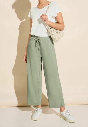 Housut, jotka ovat kevyet ja rentoa mallia, salvianvihreät, joissa on elastinen vyötärö. Yhdistetty valkoisen lyhythihaisen paidan ja valkoisten tennareiden kanssa.