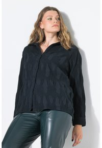 Camicia nera testurizzata con un motivo ondulato e colletto. Caratterizzata da maniche lunghe e una vestibilità rilassata, abbinata a pantaloni in pelle verde.