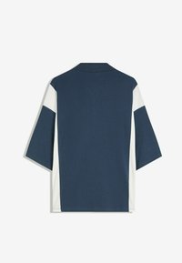 Mörkblå kortärmad polo-tröja med en vit färgblockdesign på axlarna och sidsömmarna. Slät tygtextur, klassisk krage.