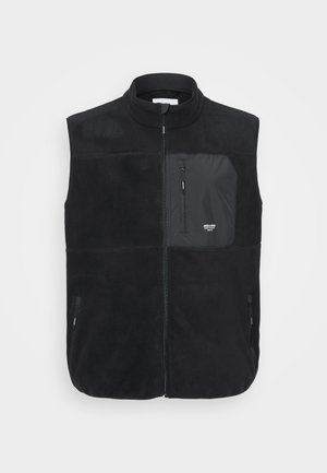 Chaleco de forro polar negro con cuello alto, cierre frontal y un bolsillo en el pecho con cremallera. Cuenta con dos bolsillos laterales y un acabado suave y texturizado.