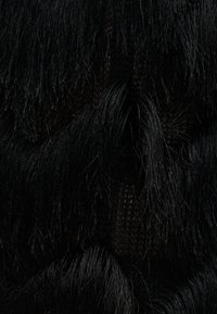 Schwarze Stofflagen mit Fransen und einem darunter sichtbaren, feinen Netzgewebe, die strukturierte und sich überlappende Textilmuster erzeugen.