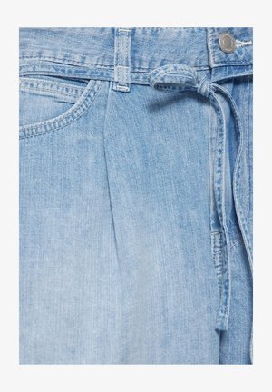Gros plan sur un pantalon en denim bleu clair avec poche avant, passants de ceinture, une ceinture en tissu nouée et une fermeture bouton en métal.
