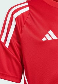 Maglietta sportiva rossa con strisce bianche sulle spalle. Realizzata in tessuto liscio, presenta un logo bianco sull'area sinistra del petto.