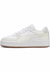 Vitt sportskor med en blandning av läder och mocka, med en platt gummisula, perforerad tå och en texturerad hälaccent.