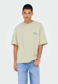 Hellgrünes, oversized T-Shirt aus Baumwolle. Bietet einen gerippten Rundhalsausschnitt, kurze Ärmel und ein kleines Markenlogo auf der linken Brust.