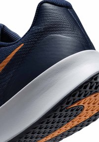 Chaussure de sport avec une tige en maille bleu marine et des accents en cuir texturé, semelle intermédiaire blanche et semelle extérieure noire avec un détail de logo orange.