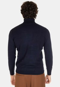 Maglione a collo alto blu navy realizzato in tessuto a maglia, con maniche lunghe e orlo a coste. Texture liscia con silhouette aderente.