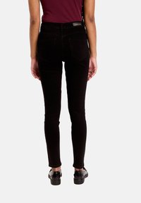 Jean skinny noir taille haute, avec un design classique à cinq poches et des détails de couture subtils sur les poches arrière.
