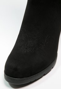 Botín negro de ante hasta el tobillo con bordado floral en el lateral, puntera redonda y suela de goma texturizada para un mejor agarre.