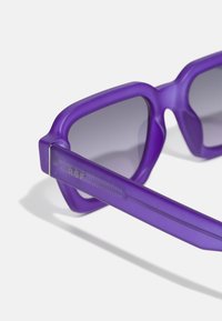 Lilla solbriller med matt finish, vinkelramme og gradient grå linser. Sidefunksjonene har gravert tekst og en strømlinjeformet tempeldesign.