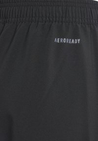 Schwarze Sportshorts aus glattem Material mit einem elastischen Bündchen. Mit "AEROREADY" Logo in hellgrau nahe der Oberkante.
