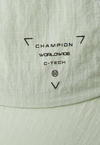 Casquette vert clair avec texture en grille, comportant un texte noir « Champion Worldwide C-Tech ». Inclut des accents graphiques.