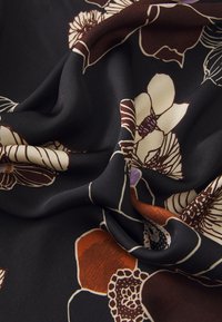 Black fabric featuring large floral patterns in cream, brown, and hints of purple. The texture is soft and flowing, with vibrant color contrasts.