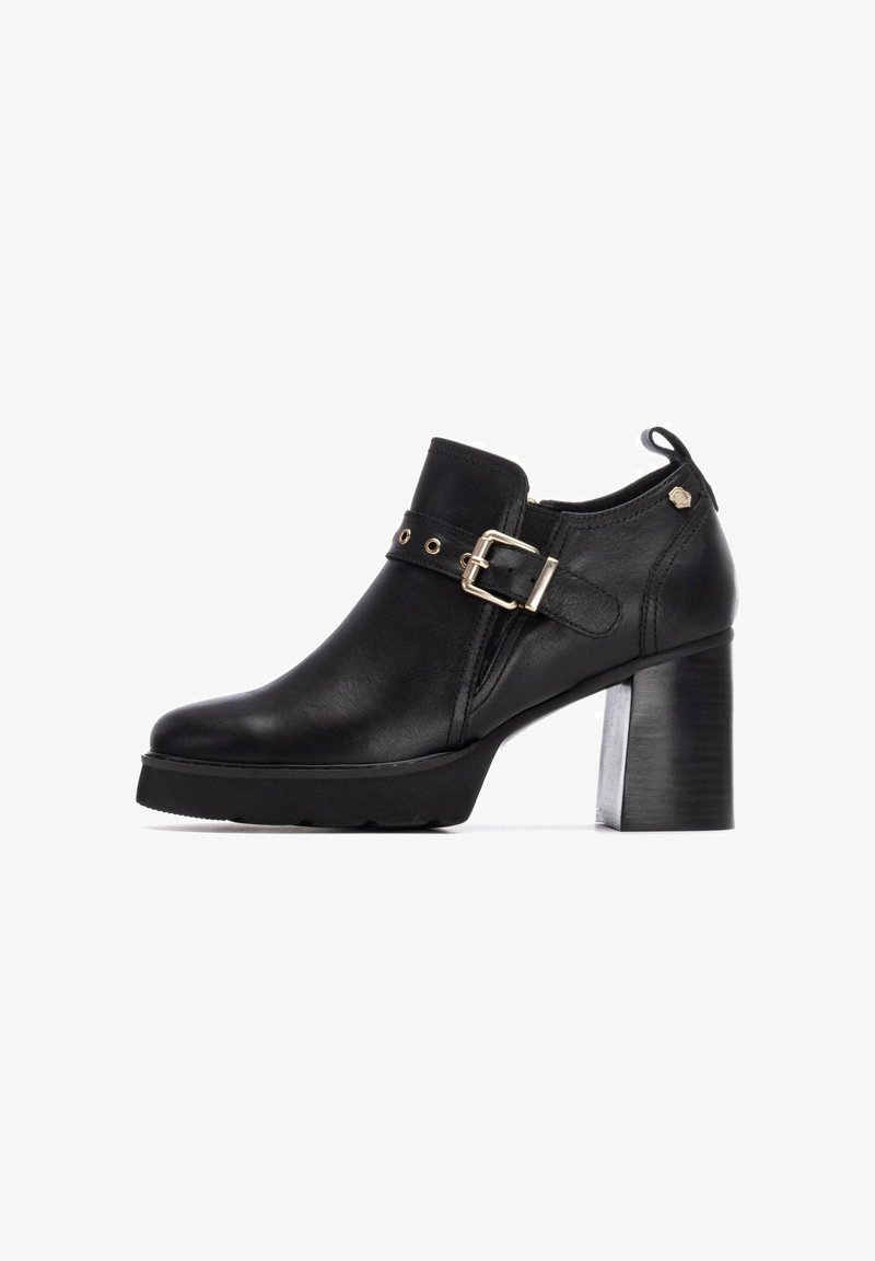 Bottines noires en cuir avec un talon épais, ornées d'une sangle à boucle et de détails en métal doré. Texture lisse et design à bout arrondi.