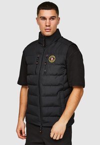 Zwarte puffer vest met hoge kraag, rits aan de voorkant, twee borstzakken en geborduurd logo. Glad textuur met horizontale stikseldetails.