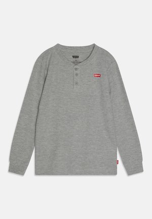 Chemise Henley grise à manches longues avec trois boutons, texture côtelée, et logo Levi's rouge sur la poitrine gauche et la couture latérale.