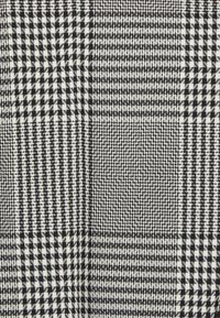 Tissu à motifs noir et blanc présentant un mélange de motifs pied-de-poule, carreaux et vichy de tailles et textures variées.