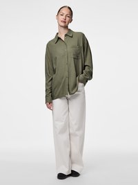 Olijfgroene overhemd met knopen en een borstzak, gecombineerd met crèmekleurige wijde broek met een ontspannen pasvorm en een eenvoudig ontwerp.