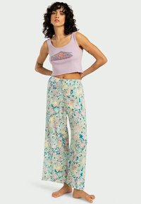 Light purple cropped tank top with "Billabong" logo, paired with loose, multi-colored tie-dye pants featuring pastel blue, pink, and green patterns.