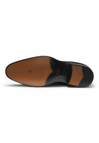 Suola di scarpa in pelle nera con una finitura liscia. Presenta un accento in pelle color cuoio e cuciture decorative. Design pulito e minimalista.