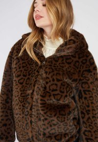 Brązowa kurtka z sztucznego futra z czarnym nadrukiem w panterkę, zamek błyskawiczny, kaptur i przednia kieszeń; miękka tekstura, luźny krój i casualowy design.