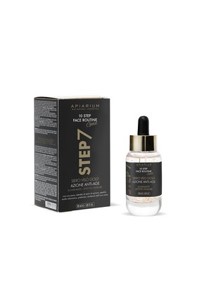 Siero viso anti-età Step 7 con scaglie d'oro in un flacone con contagocce accanto alla confezione del prodotto nera e dorata.