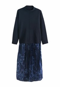 Pull à manches longues bleu marine foncé associé à une jupe plissée bleu marine présentant un motif floral subtil.