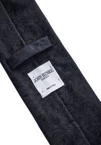 Svart fluga av texturerat tyg med virvlande mönster, med en krokstängning och en etikett som säger "JOHN HENRIC SWEDEN, Made in Italy."