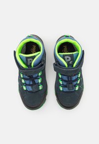 Chaussures en daim bleu marine avec des accents verts, sangle réglable, semelle texturée et doublure bleue contrastante. Conçues pour le confort et le soutien.