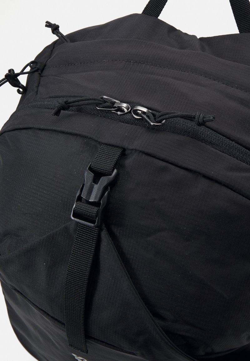Sac de sport noir doté d'un tissu texturé, de bretelles réglables, de double zips et d'une fermeture à boucle robuste pour un transport sécurisé.