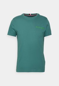 Teal kortærmet crew neck t-shirt med "HILFIGER" tekst i grøn på venstre bryst, vist mod en ensfarvet hvid baggrund.