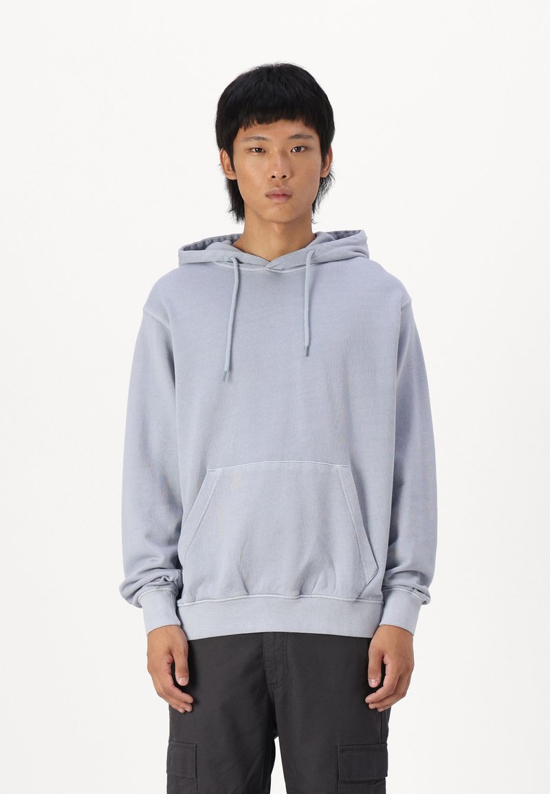 Lys grå hættejakke med snore, frontlomme og ribbede ærmer. Stoffet ser blødt ud med en afslappet pasform og minimal udsmykning.