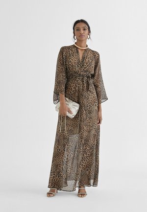 Vestido maxi de estampado de leopardo con mangas largas y cinturón en la cintura; hecho de un tejido ligero y transparente; combinado con un pequeño bolso de mano plateado.