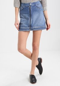 Denim-mini hame, jossa on edessä vetoketju, vaalea sininen väri, haalistunut rakenne ja koristeellista tähden kirjontaa vasemmalla puolella.