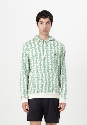 Sudadera con capucha de tejido suave, con una base blanca y patrones geométricos en verde. Incluye un bolsillo frontal y puños de canalé.