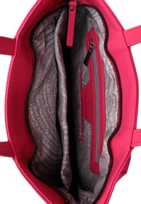 Bolso rosa con un exterior liso, cierre de cremallera y un interior forrado que incluye bolsillos, uno de ellos con cremallera, y un patrón de texto.