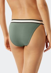 Grüner, gerippter Bikiniunterteil mit einem schwarz-weißen gestreiften Bund, ausgestattet mit einem hochgeschnittenen Design und glatter Textur.